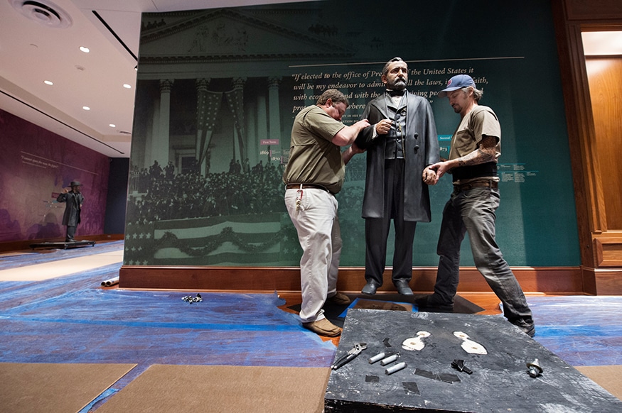 Two men prepare a statue of Ulysses S. Grant for display in a museum.